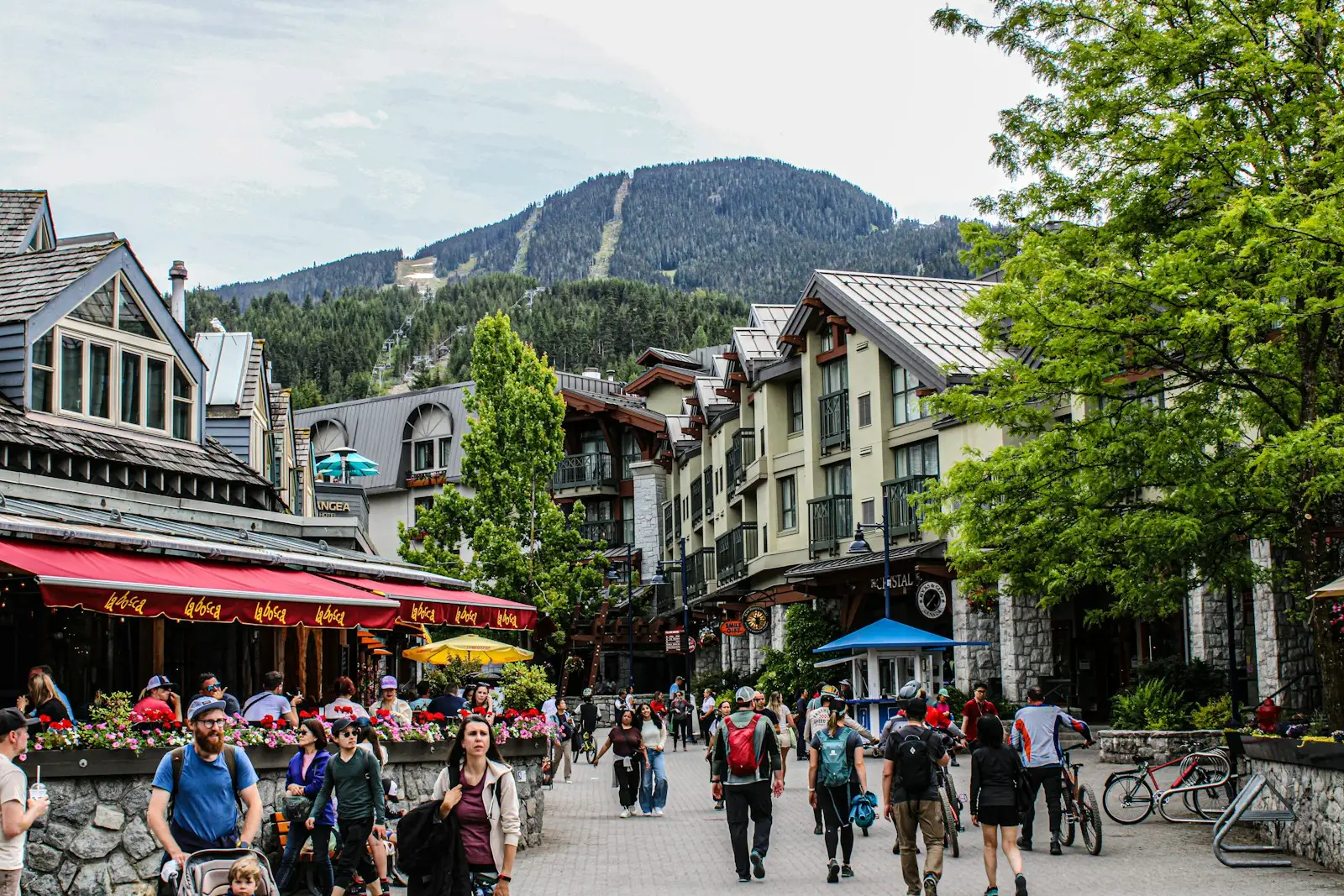 People walking a pedestrian street lined with tall timber buildings in Whistler, British Columbia.